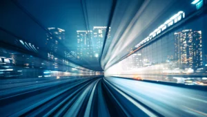 View from a fast-moving train at night, showing blurred city lights and tracks streaking forward, conveying high speed and urban energy.