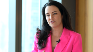 Lily Perez of Vista Equity Partners with a bright pink blazer speaking, with a lapel microphone attached.