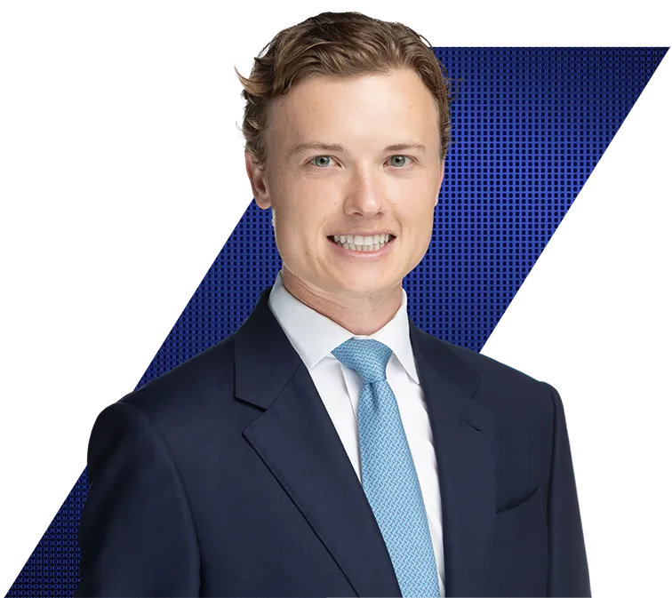 Headshot of a smiling young man in a dark blue suit and light blue tie against a black and blue geometric background.