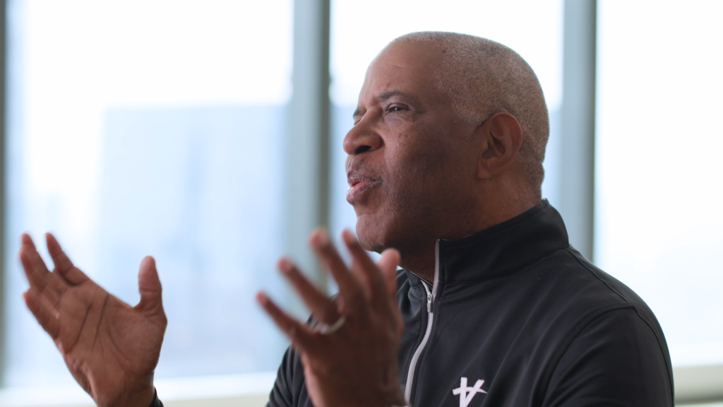 Robert F. Smith of Vista Equity Partners wearing a black zip-up with a the Vista "V" logo in white speaking.
