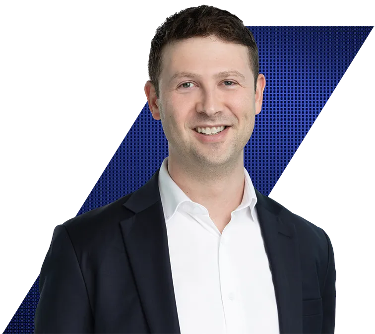 Headshot of a smiling man in a dark suit jacket and white shirt against a black and blue geometric background.