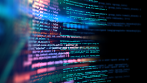 Close-up of glowing computer code in vibrant blue, purple, and red hues on a dark background, with some lines in focus and others blurred.