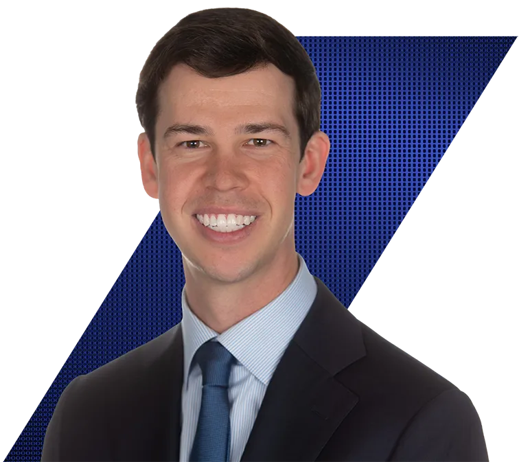 Headshot of a smiling man in a dark suit, striped shirt, and blue tie against a black and blue patterned background.