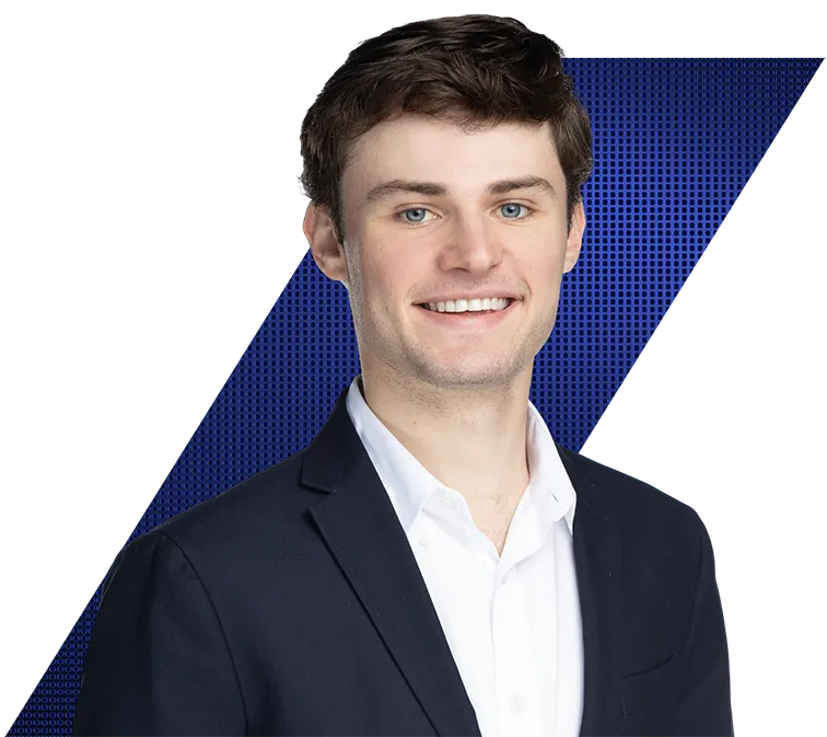 Headshot of a smiling young man with dark hair and blue eyes, wearing a suit jacket and white shirt, against a black and blue patterned background.